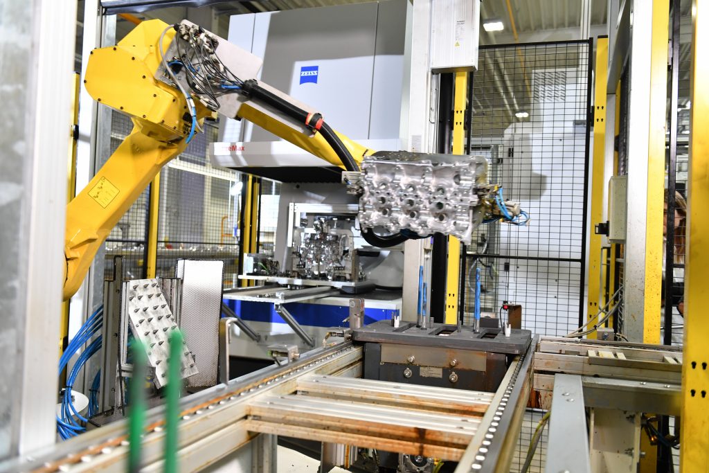 Die Inline-Messstation von Zeiss ist komplett automatisiert: Ein Roboterarm greift die ankommende Zylinderkopfhaube. (Bild: Carl Zeiss Industrielle Messtechnik GmbH)